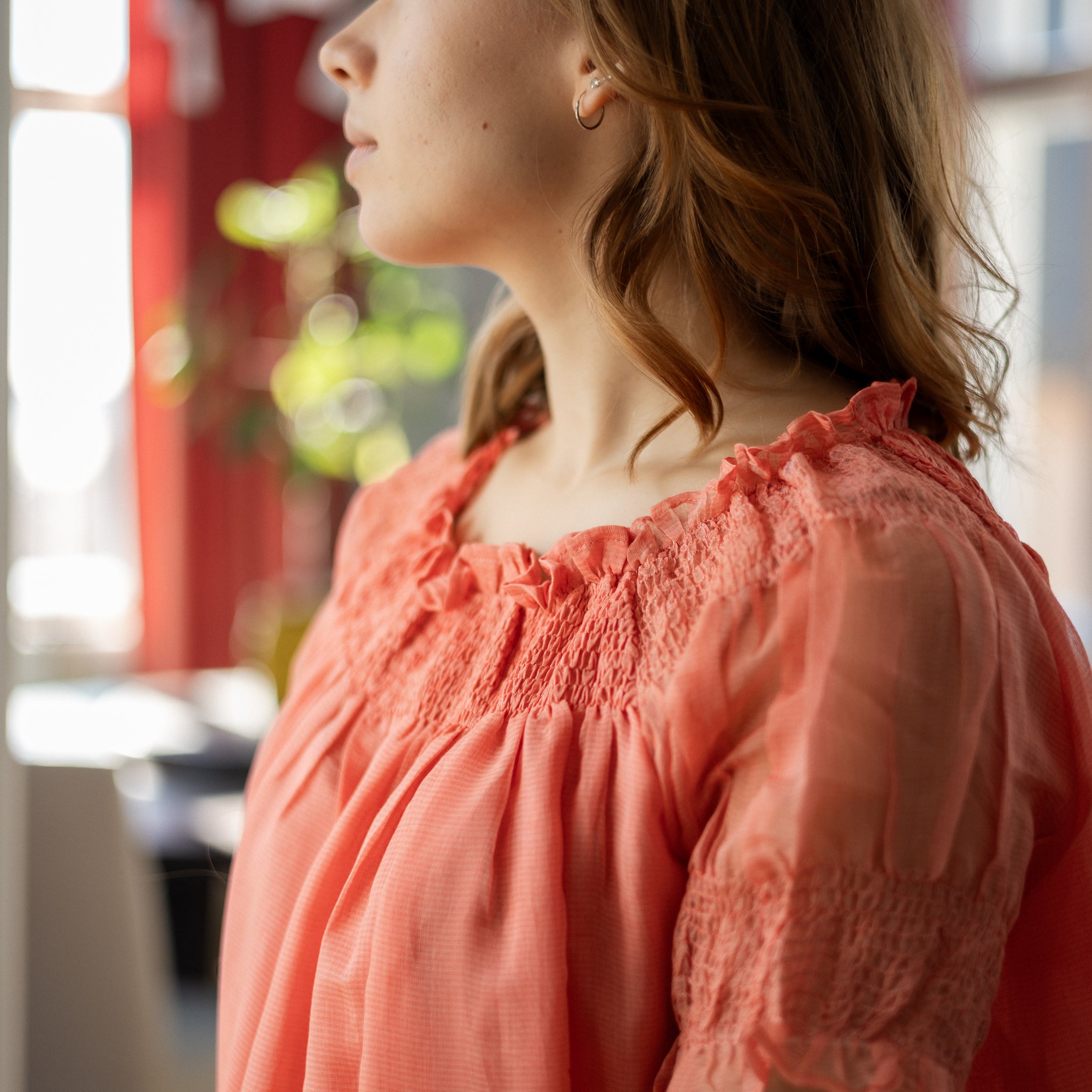 Woman wearing a pink blouse with a blurred indoor background