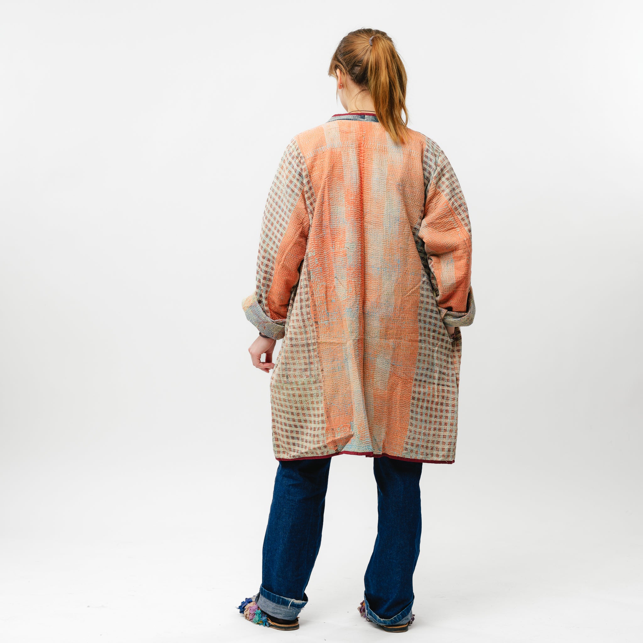 Person wearing a long, patterned coat with a white background