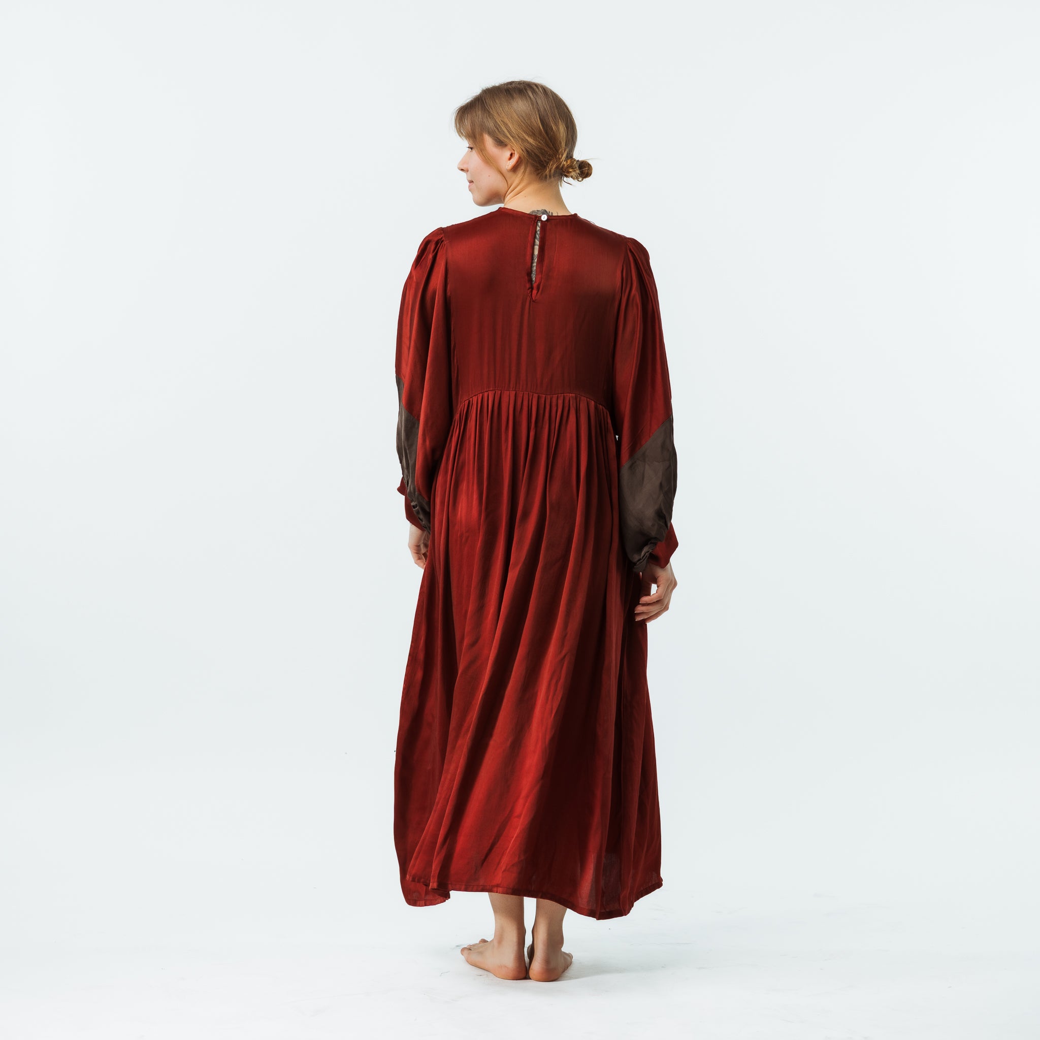 Woman wearing a red dress with sheer sleeves on a white background