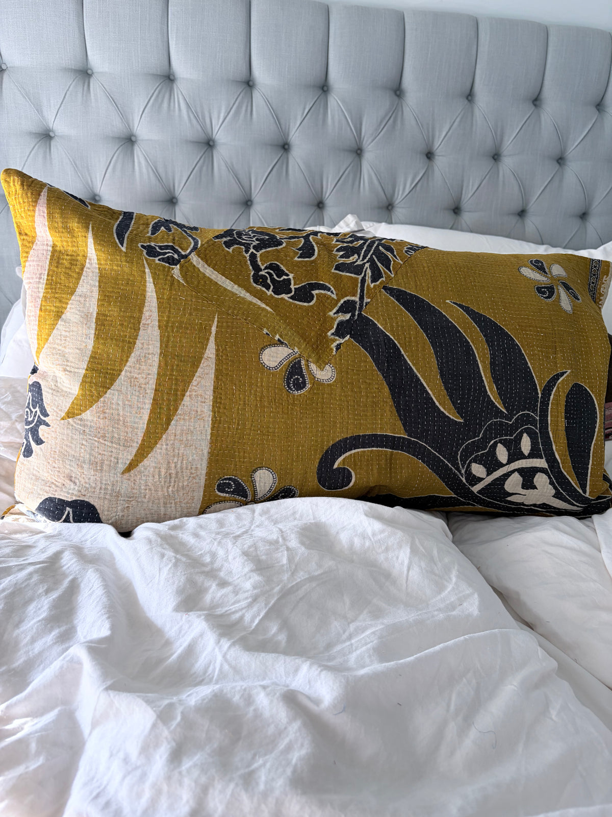 vintage Kantha pillow on bed with large flower 
